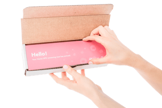 Hands opening a brown box containing a pink package labeled
