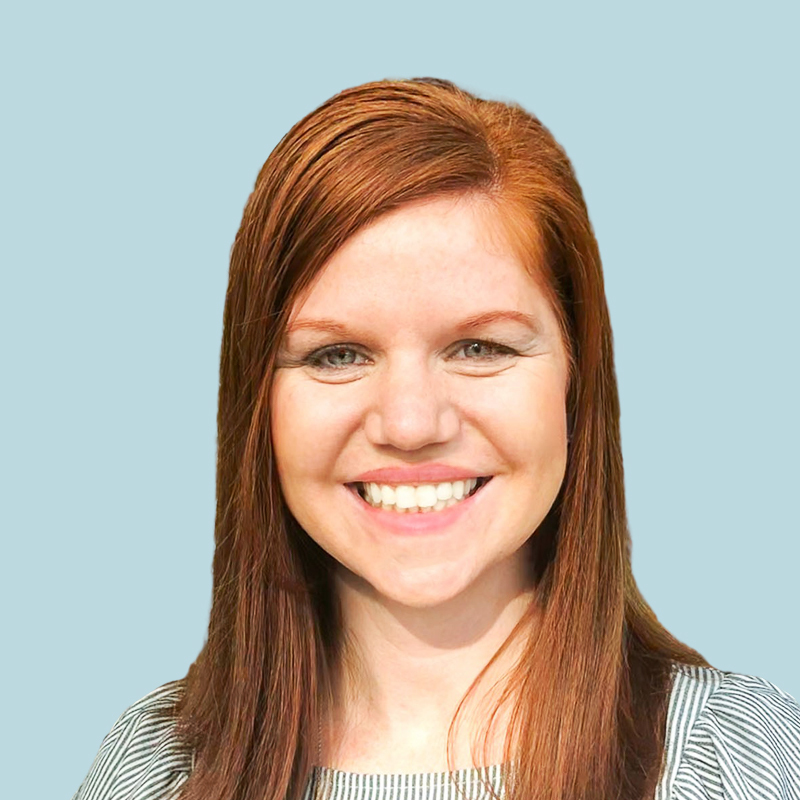 Smiling person with long red hair against a light blue background.