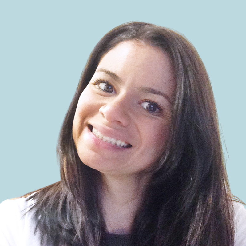 A person with long dark hair smiling against a light blue background.