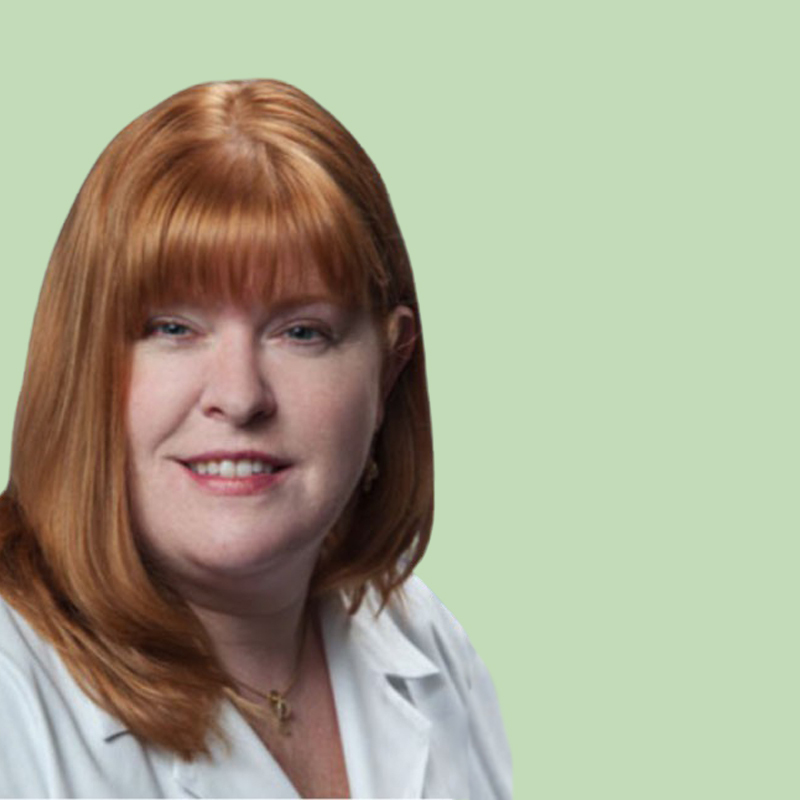 A person with long red hair and a white collared shirt is smiling against a light green background.