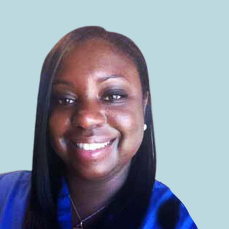 A person with long black hair is smiling, wearing a blue shirt, against a light blue background.