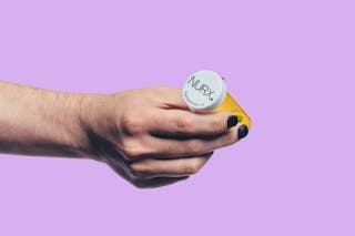 Hand holding a yellow prescription bottle with a white cap, labeled 