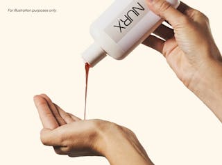 Hands pouring liquid from a bottle labeled 