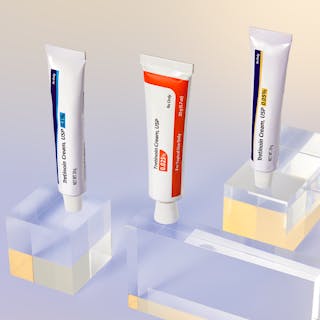 Three tubes of Tretinoin Cream USP with varying strengths grace clear acrylic blocks, set against a gradient backdrop.