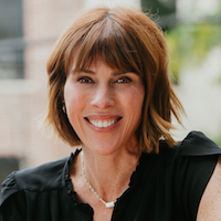 A woman with short brown hair and a black blouse smiles at the camera.