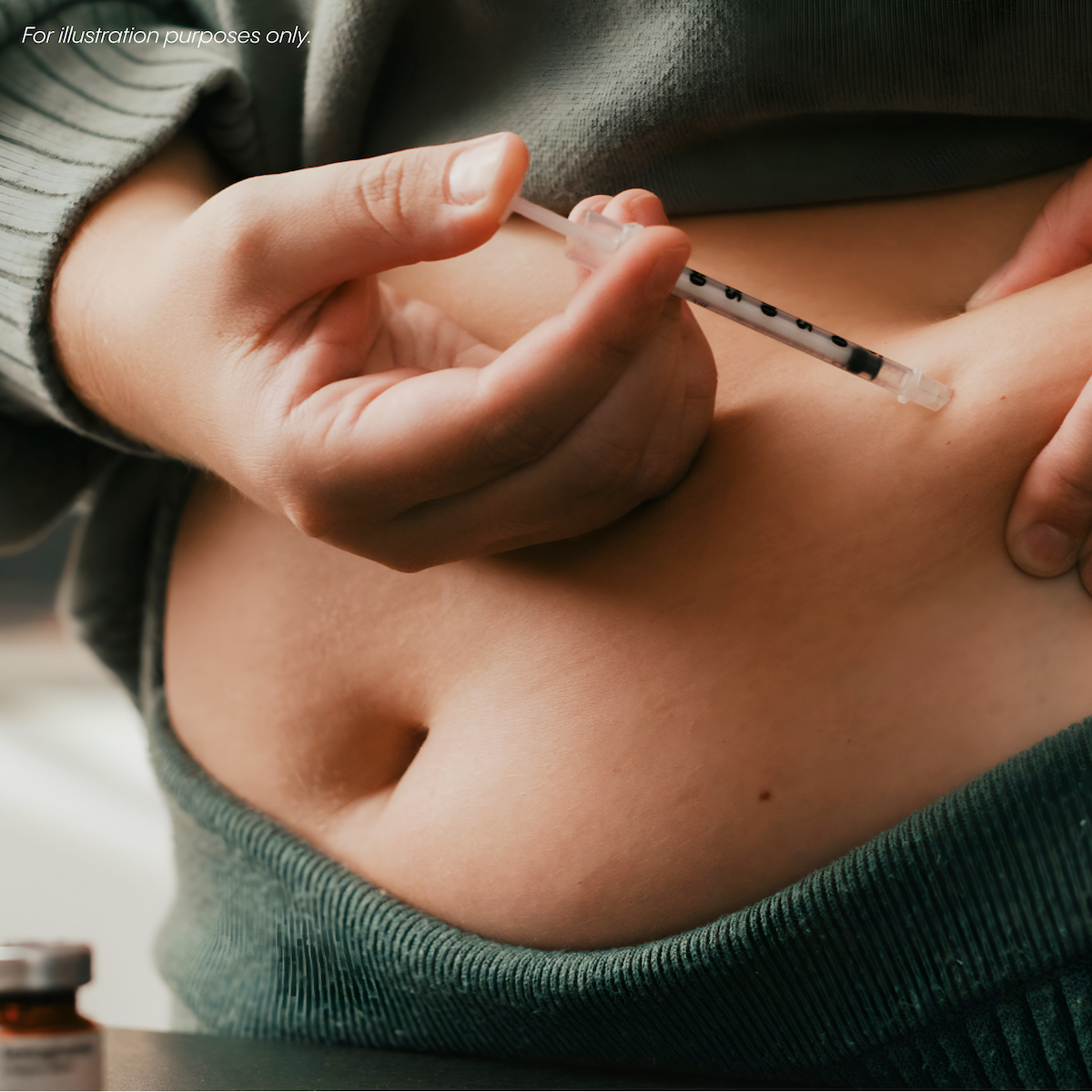 Person administering an injection into their abdomen using a syringe.