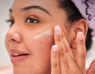 Women applying a topical cream to her face