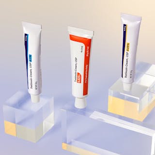 Three tubes of Tretinoin Cream USP with different percentages are displayed upright on clear acrylic blocks against a gradient background, highlighting the versatility of Tretinoin Cream for various skincare needs.